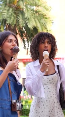 Çeşitli bayan arkadaşlar dondurma külahlarının tadını çıkarırken, neşe ve bağlantı yayarken güneşli şehir caddesinde kaygısızca vakit geçiriyorlar.