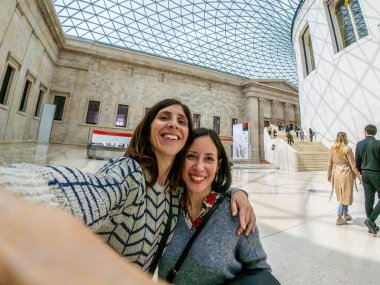 İki neşeli bayan turist, Londra 'daki İngiliz müzesinin muhteşem sarayında eğlenirken selfie çekiyorlar.