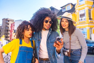 Turistler, Valparaiso, Chile 'deki canlı ve renkli evlerin önünde gülümseyip eğleniyorlar, akıllı telefonlarla anları yakalıyorlar.