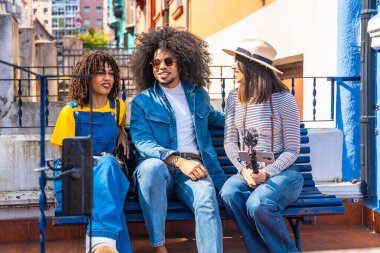 Üç genç içerik yaratıcısı akıllı telefon ve mikrofon kullanarak açık havada bir podcast kaydediyor.