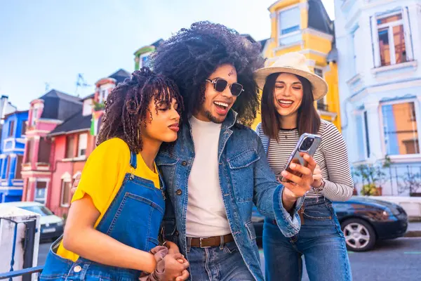 Caminito Caddesi, la boca Mahallesi, Buenos Aires 'teki renkli evlerin önünde üç turist akıllı telefon kullanıyor.