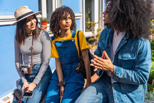 Üç genç içerik yaratıcısı video içeriği planlıyorlar sokakta oturmuş fikirleri tartışıyor ve paylaşıyorlar.