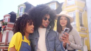 Üç neşeli arkadaş, birlikte dışarıda vakit geçiriyorlar, sosyal medyada geziniyorlar ve akıllı telefondan gördükleri bir şeye gülüyorlar.