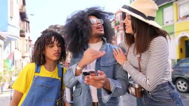 Üç arkadaş, iki kadın ve bir erkek, canlı bir şehri keşfediyorlar, yön bulmak için akıllı telefon kullanıyorlar, canlı sohbetler yapıyorlar.