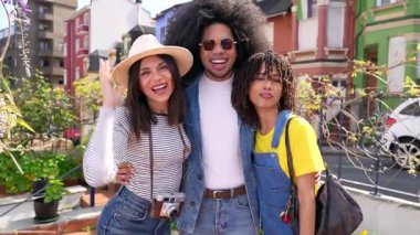 Canlı bir şehir ortamında fotoğraf çektirmek için poz veren üç neşeli turist seyahat maceralarının anılarını yakalıyorlar.