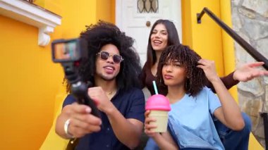 Genç nüfuzlu kişiler vlog kaydediyor, yaz tatilinde canlı sarı kapı eşiğinde milkshake yudumluyorlar.