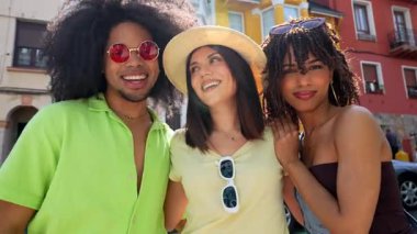 Çok ırklı genç arkadaşlar güneşli yaz tatilinin tadını çıkarıyorlar, neşe ve kaygısız enerjiyle birlikte gülerek ve şehir sokaklarını keşfediyorlar.