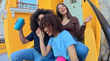 Üç arkadaş, canlı sarı bir duvarın önünde oturmuş, kahkahaları ve sohbetleri içkilerimizi içerken paylaşıyorlar.