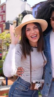 Turist çiftler tatilin tadını çıkarıyorlar, renkli bir mahallede poz veriyorlar ve gülümsüyorlar.