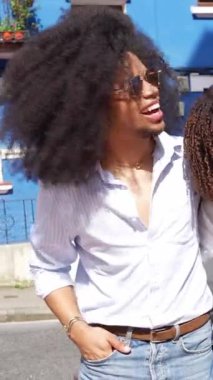 Genç turistler tatilde eğleniyorlar, gülümsüyorlar ve mavi bir binanın önünde poz veriyorlar.