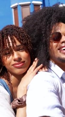 Bir grup neşeli çoklu etnik arkadaş renkli binalarla dolu canlı bir sokakta komik selfie çekiyorlar.