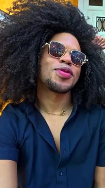 Neşeli çoklu etnik arkadaşlar selfie çekiyor, gülüyor ve kaynaşıyorlar. Güneşli yaz gününde canlı sarı şehir merdivenlerinde oturuyorlar.