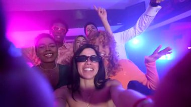 Genç yetişkinler canlı bir gece kulübü atmosferinin tadını çıkarırlar. Dans ve renkli ışıkların arasında selfie çekerek anılarını yakalarlar.