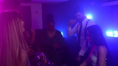 Genç insanlar gece hayatını seviyorlar, vücutlarını hareket ettiriyorlar ve renkli ışıklar altında ponpon sallıyorlar.