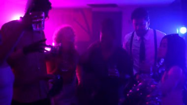 Bir gece kulübünde dans eden ve içen enerjik arkadaşlar, canlı mor ve mavi ışıklarla aydınlatılıyor.