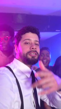 Gece kulübü partisinde arkadaşlarıyla dans eden ve müzikle eğlenen enerjik bir adam neşeli anılar yaratıyor.