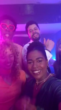 Neşeli arkadaşlar dans ediyor ve gece hayatından zevk alıyor, selfie çekiyor ve gece kulübünde birlikte eğleniyorlar.