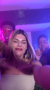 Neşeli arkadaşlar gece hayatının tadını çıkarıyor, renkli ışıklar altında selfie çekiyor ve gece kulübü partisinde dans ediyor.