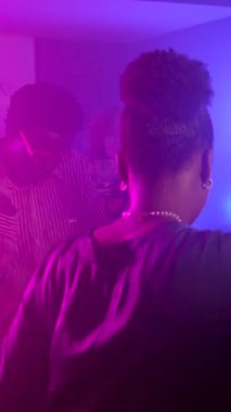 Genç arkadaşlar yüksek enerjiyle parti yapıyorlar. Canlı mor ışıklar altında ritmik bir şekilde dans ediyorlar. Saf neşe ve bağlantı anlarını paylaşıyorlar.