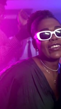 Gece kulübünde renkli ışıklar altında enerjik bir şekilde dans eden genç kadınlar müzik ve gece hayatından zevk alıyorlar.