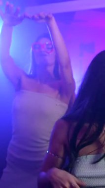 Gece hayatının tadını çıkaran çeşitli kadın arkadaş grupları canlı, loş bir kulüpte ritmik olarak müziğe yöneldiler.