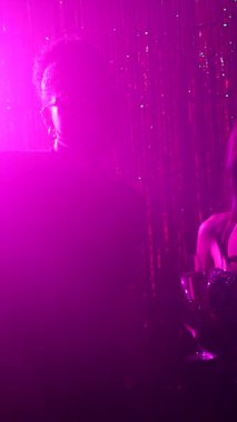 Enerjik drag queen canlı gece kulübü atmosferinde mikrofon performansı ile büyüleyici izleyici kitlesi