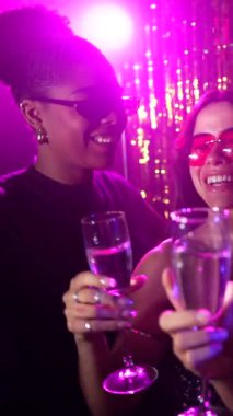 Genç kadınlar canlı bir disko partisinden zevk alıyorlar, kadehlerini kaldırıyorlar, renkli neon ışıklarla yıkanıyorlar.