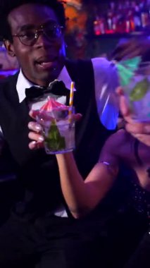 Arkadaşlar kadehlerini kaldırır, kokteyllerin tadını çıkarır ve canlı bir barda birbirlerine eşlik ederler.