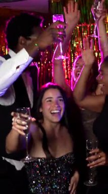 Çok ırklı arkadaşlar enerjik bir dansla kutlama yapıyorlar. Canlı bir gece kulübü partisinde şampanya kadehleri kaldırıyorlar. Neşe ve dostluk saçıyorlar.