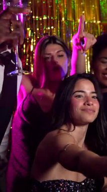 Neşeli çoklu etnik arkadaşlar poz veriyor, gülümsüyor ve eğleniyorlar, göz alıcı bir partide fotoğraf çekiyorlar.