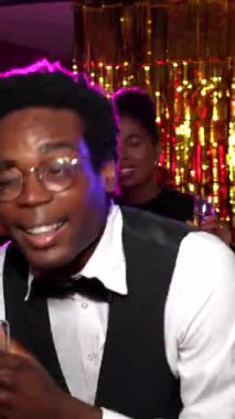 Genç Afrikalı Amerikalı garson, yeni yıl partisinde enerjik bir şekilde dans ediyor, gece kulübünde arkadaşlarıyla ve meslektaşlarıyla neşe paylaşıyor, şampanya içiyor ve kutlama anının tadını çıkarıyor.