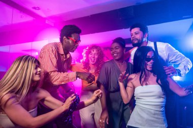 Neşeli çoklu etnik arkadaşlar dans ediyor ve neon ışıklı disko kulübünde gece hayatının tadını çıkarıyorlar.