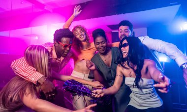 Neşeli çoklu etnik arkadaşlar gece hayatının tadını çıkarıyor, dans ediyor ve disko partisinde birlikte eğleniyorlar.