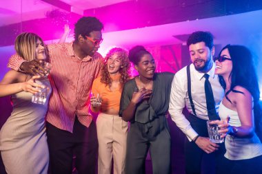 Genç insanlar, renkli ışıklar ve şenlikli konfetiyle çevrili canlı bir gece kulübünün partisinde gülüp eğleniyorlar.