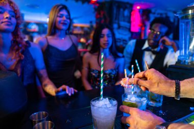 Barmen, müşterilerin izlediği kalabalık bir gece kulübündeki canlandırıcı kokteyllere son rötuşları da ekliyor.