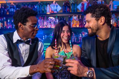 Mutlu arkadaşlar gece kulübünde kokteyl içiyor, bardakları kaldırıyor ve canlı bar atmosferinde kutlama için kadeh kaldırıyorlar.