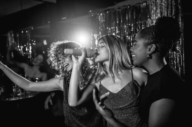 Bir grup arkadaş karaoke gecesinde neşeli bir şekilde şarkı söylüyor, birlikte vakit geçiriyorlar ve canlı bir gece kulübünde unutulmaz anılar yaratıyorlar.
