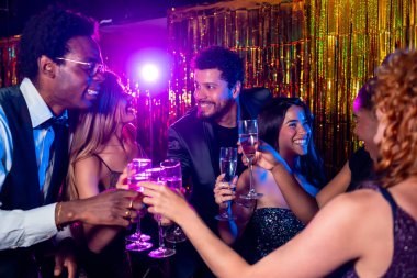 Neşeli zarif arkadaşlar kadehlerini şampanya kadehleriyle kaldırıyor. Bir gece kulübünde muhteşem bir partinin tadını çıkarıyorlar.