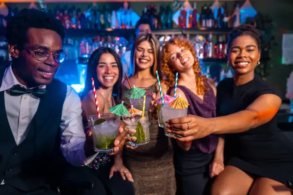 Çeşitli arkadaş grupları coşkulu bir gece kulübünde mojito kadehleri kaldırarak gece hayatı ve arkadaşlığın tadını çıkarıyor.