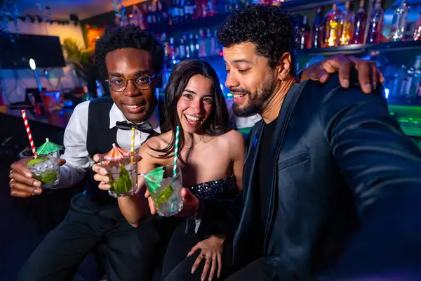 Mutlu arkadaşlar barda kokteyl içerken selfie çekiyorlar, dışarıda eğleniyorlar.