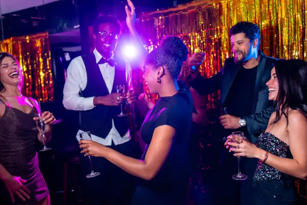 Neşeli çoklu etnik arkadaşlar dans ediyor, kokteyl içiyor, gece kulübünün partisinde birlikte eğleniyorlar.