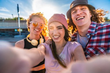 Üç neşeli arkadaş güneşli bir günün tadını çıkarıyorlar, birlikte neşeli anları yakalıyorlar ve canlı bir selfie çekiyorlar.