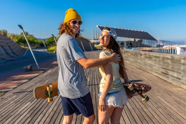 Güneşli bir sahil yolunda kaykay yapan genç yetişkinler kaygısız yaz eğlencesi ve şehir ortamında arkadaşlığın özünü yakalıyorlar.