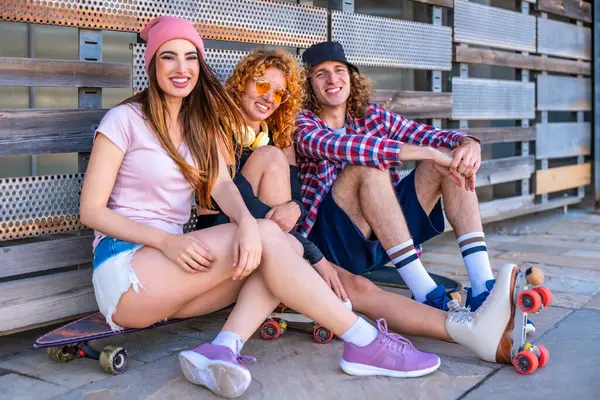 Çeşitli genç arkadaşlar birlikte dışarıda vakit geçiriyorlar. Milenyum kaykaycıları günlük kıyafetler giyer ve bereler şehir ortamında samimi bir gülümseme sergilerler.