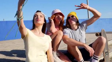 Genç patenciler güneşli sahil şeridi boyunca neşeli selfie 'ler yaratarak yaz arkadaşlığını ve tasasız anları mobil teknolojiyle yakalıyorlar.