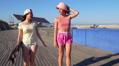 Yürüyüş yapan ve konuşan bayan arkadaşlar, güneşli yaz günlerinde okyanus kıyısı yakınlarında keyifli bir gezinti yaparak bağlantı anlarını paylaşıyorlar.