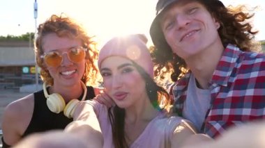 Genç arkadaşlar, grup selfie çekerken unutulmaz anları yakalıyorlar. Altın gün batımı ışığında kaygısız açık hava etkileşiminin tadını çıkarıyorlar.