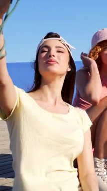 Bir grup neşeli arkadaş, ahşap iskelede selfie çekerken hatırlanmaya değer anları yakalıyor güneşli bir yaz gününün tadını çıkarıyorlar.