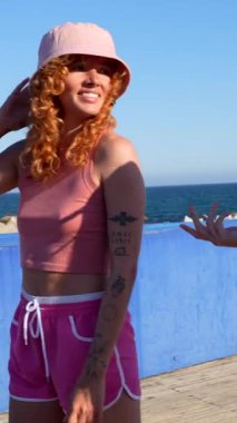 Kumsalda güneşli bir günün tadını çıkaran iki neşeli genç kadın bir an kahkaha ve mutluluk paylaşıyor.