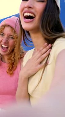 Bir grup neşeli genç arkadaş selfie çekiyor ve mavi ve sarı arka planda komik suratlar takınıyorlar.